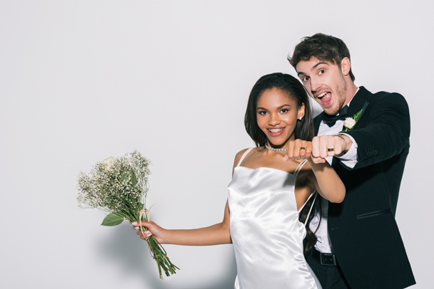 happy interracial newlyweds showing wedding rings on their hands on white background - Photo, image