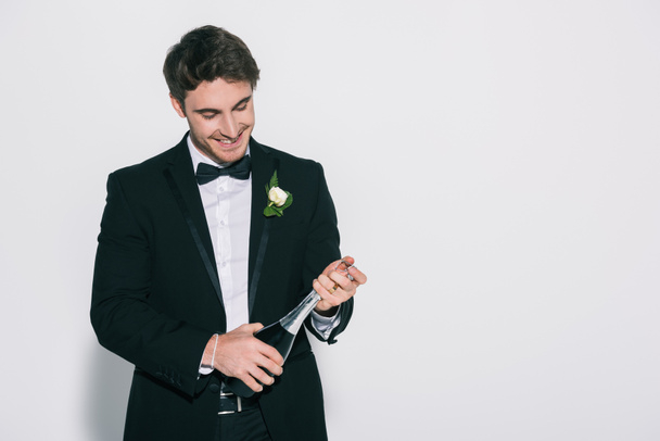 happy bridegroom opening champagne bottle on white background - Zdjęcie, obraz