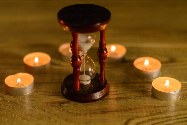 The concept of time. Hourglass and burning candles. - Fotó, kép