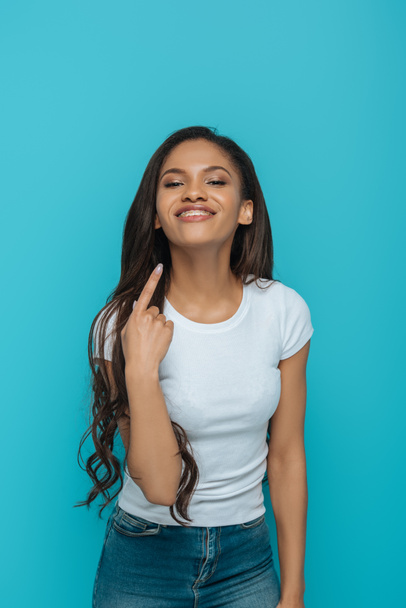 boldog afro-amerikai lány mutató fogszabályzó a fogai elszigetelt kék - Fotó, kép