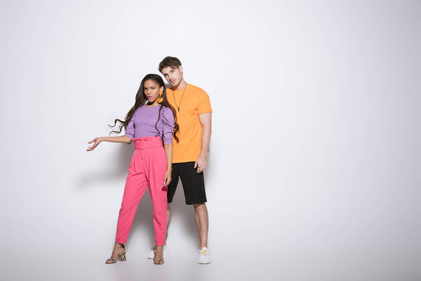 full length view of trendy african american girl standing with open arm near handsome boyfriend on white background - Foto, Imagen