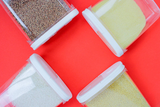 voedseldonatie boekweit, pasta, rijst, gierst, griesmeel. concept set van quarantaine voedsel rode achtergrond - Foto, afbeelding