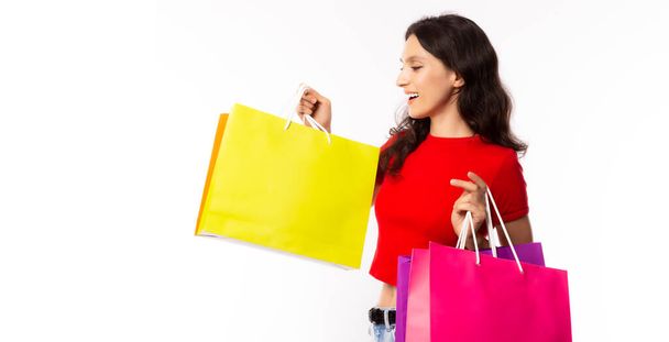 Krásná nakupující žena nosí nákupní tašky se štěstím, smajlíkem. Atraktivní krásná běloška si užívá čas nakupování. Ráda nakupuje zboží, když je to prodej, sleva - Fotografie, Obrázek