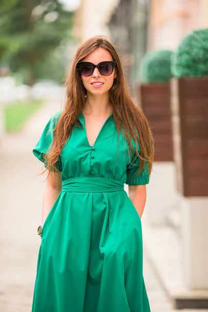 Fiatal nő zöld ruhában a városban - Fotó, kép
