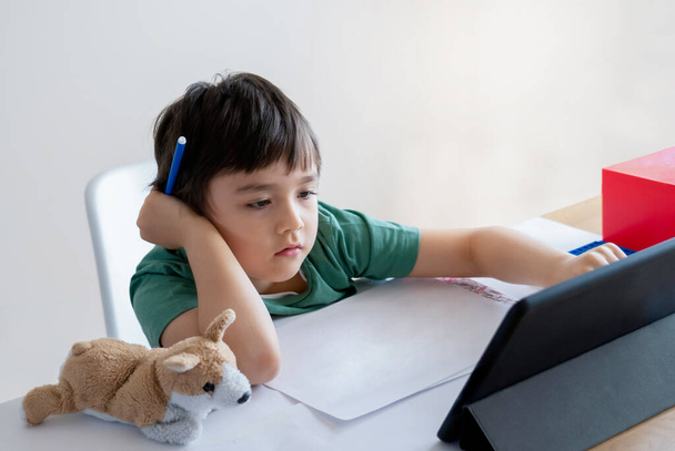 Kind selbstisoliert mit Computer für seine Hausaufgaben, Kind mit Laptop Informationen im Internet suchen, während der Schule während covid-19 Lock-down, Social Distancing, Lernen Online-Bildung - Foto, Bild