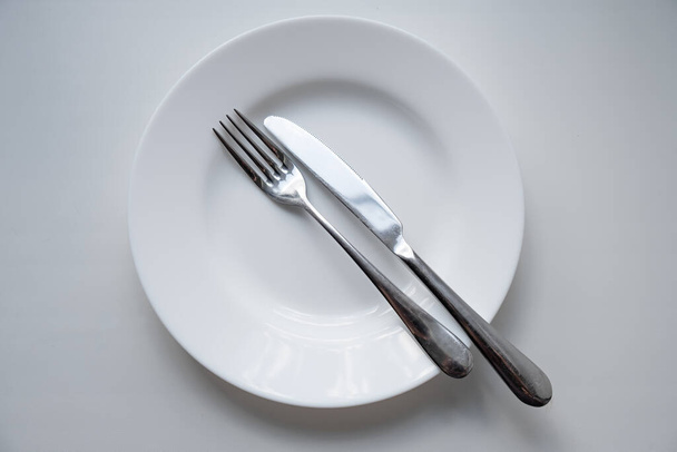 A white plate with a fork and knife - Valokuva, kuva