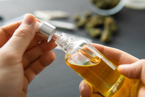 Hand holding bottle of Cannabis oil in pipette, close up, natural herb, medical marijuana concept, CBD cannabis OIL. hemp product, - Photo, Image