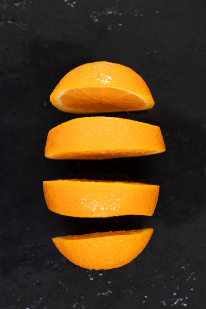 Ζουμερό πορτοκάλι κομμένο σε φέτες με εκπτώσεις, μαυρισμένο σε πλάκα γρανίτη με νερό - Φωτογραφία, εικόνα