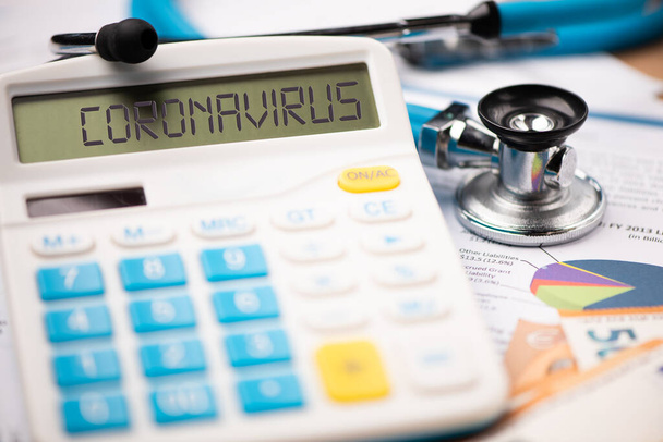 Coronavirus járvány és annak pénzügyi következményei. Egy számológép a szó CORONAVIRUS közelről - Fotó, kép