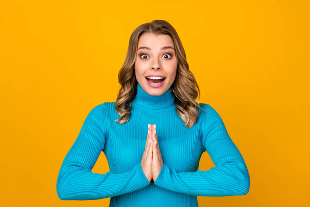 Photo of attractive funny curly lady arms together pleading boyfriend buy her new dress excited good mood wear casual blue warm turtleneck isolated yellow color background - Valokuva, kuva