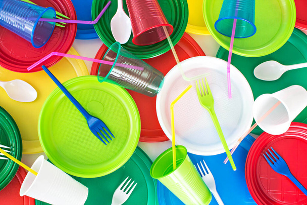 Élénk színű eldobható műanyag evőeszközök háttér. Piknik díszlet. Ökológia probléma. Felülnézet. - Fotó, kép