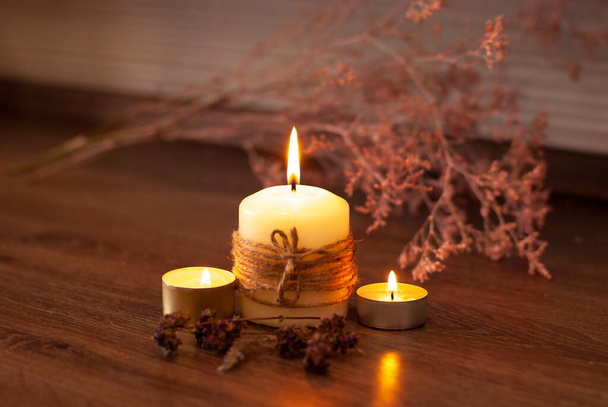 Aromatherapy flame closeup picture Beautyful burning light yellow vanilla candles with wooden background and dry flowers - Foto, Imagem