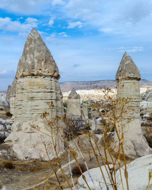The volcanic landscape of valley with natural rock formations known as fairy chimneys, located near Goreme town, Cappadocia region of Turkey - Fotoğraf, Görsel