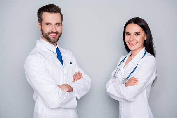 Photo of handsome doc guy professional lady patient consultation virology clinic listen client toothy smiling arms crossed experienced doctors wear lab coats isolated grey color background - Φωτογραφία, εικόνα