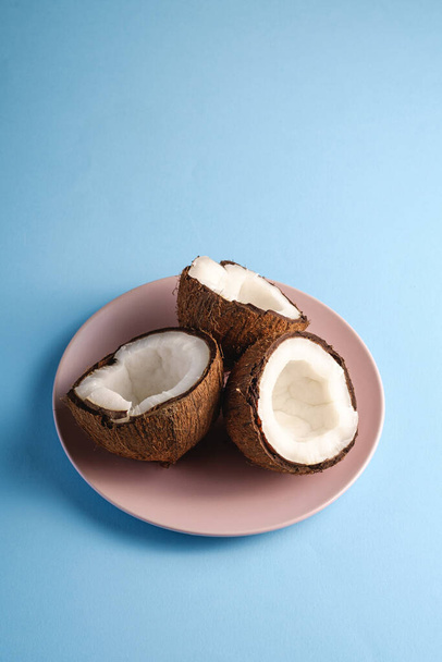Frutti di cocco in piatto rosa su sfondo blu vivace pianura, astratto concetto tropicale cibo, angolo vista copia spazio
 - Foto, immagini