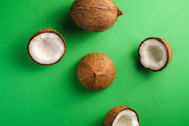 Owoce kokosowe na zielonym tle, abstrakcyjne jedzenie tropikalne koncepcja, widok z góry - Zdjęcie, obraz