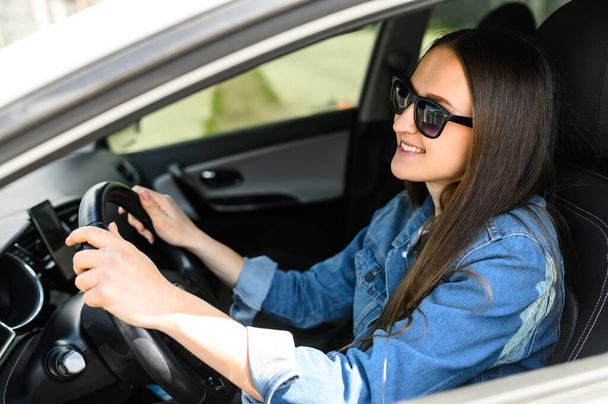 A young woman is driving a car - Фото, изображение