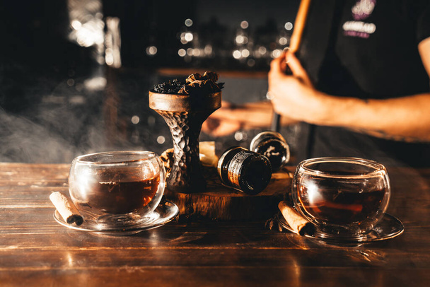 Fűszeres tea fahéjjal és ánizs csípős keleti shisha fából készült asztalon - Fotó, kép
