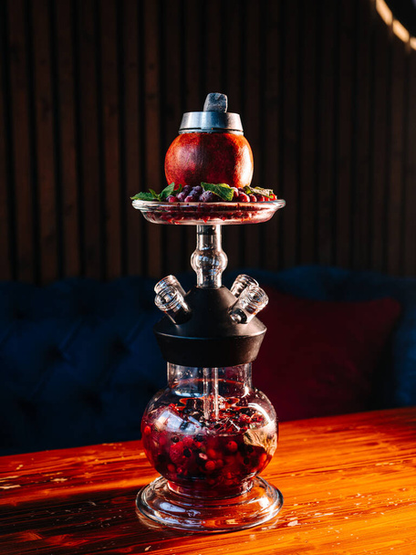 Especial en un shisha-bar: narguile de granada de fruta con bayas y jugo helado sobre fondo oscuro
 - Foto, Imagen