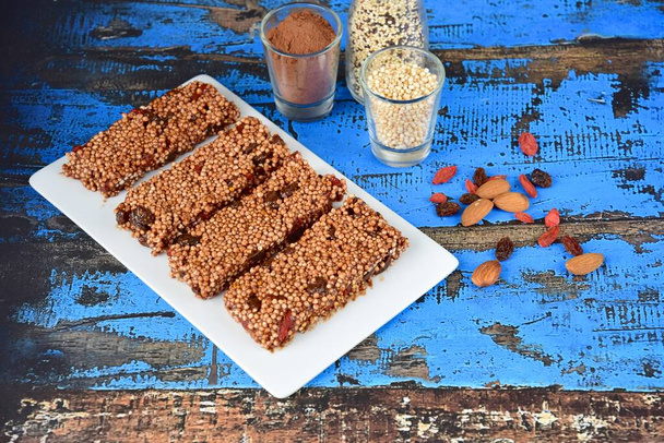 Healthy energy bars with puffed quinoa, cocoa powder, almond butter, goji berry, raisin, maple syrup and coconut butter - Photo, Image