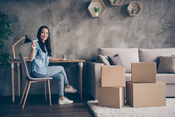 Portrait of her she nice attractive lovely pretty cheerful cheery girl sitting on chair showing plastic card paying mortgage insurance in modern loft industrial house apartment - Valokuva, kuva