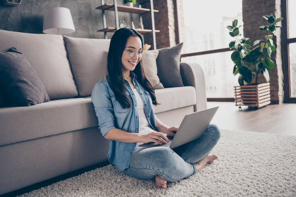 Full body profile side photo of positive cheerful girl sit carpet legs crossed folded use laptop make work management project in room indoors - Фото, зображення
