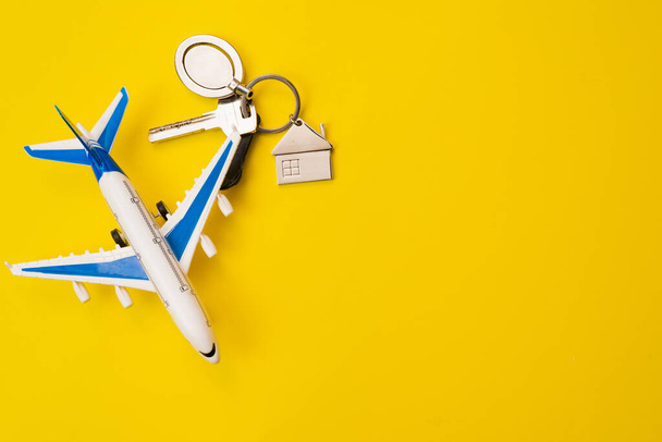 The concept of flying home, return. Airplane model and apartment keys with a keychain in the form of a house. Symbol. - Photo, Image