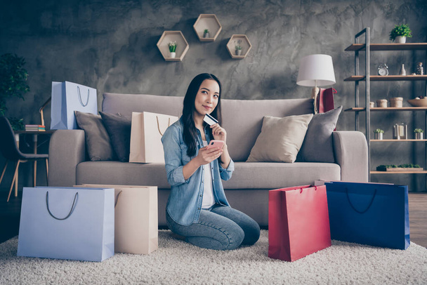Portrait of her she nice attractive lovely cheery dreamy girl sitting on carpet using device buying ordering new clothes things plastic card in modern loft industrial house apartment - Φωτογραφία, εικόνα