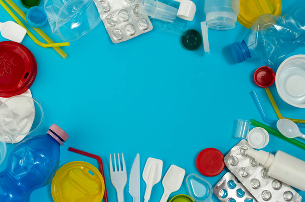 White single-use plastic and other plastic items on a blue background. The concept of choice without plastic or environmental problems. - Photo, Image