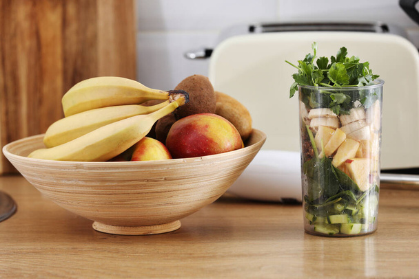 スムージー用の砕いた果物。家庭のキッチンの背景にテーブルの上に異なるトロピカルフルーツやスムージー、健康的な食生活の概念。選択的焦点 - 写真・画像