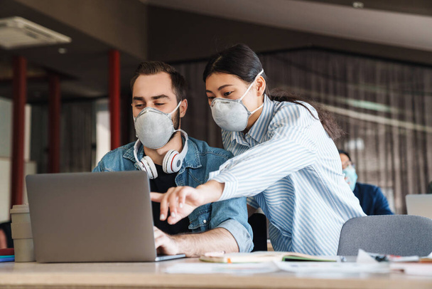 Photo of multinational young students in medical masks studying with laptop at classroom - Φωτογραφία, εικόνα