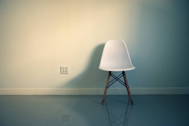 Chaise blanche avec ombre et prise de courant dans une pièce à la maison, concept de style minimaliste
. - Photo, image