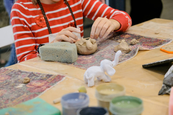Een kind vormt een product uit klei in een modellenles. - Foto, afbeelding