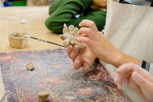 モデリングレッスンで粘土から製品を成形する子供. - 写真・画像