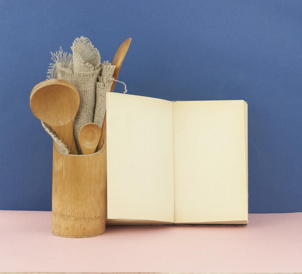 Ξύλινα επιτραπέζια σκεύη και ανοιχτό βιβλίο για συνταγές - Φωτογραφία, εικόνα
