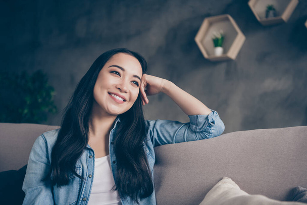 Photo of domestic pretty charming asian lady relaxing sit comfy couch staying home good mood leaning head on hand dreamer quarantine time living room indoors - Фото, зображення