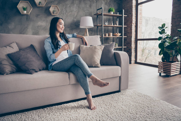 Portrait of her she nice attractive lovely charming cheerful dreamy girl sitting on divan alone drinking cacao resting weekend in modern loft industrial house apartment flat - Foto, Imagem