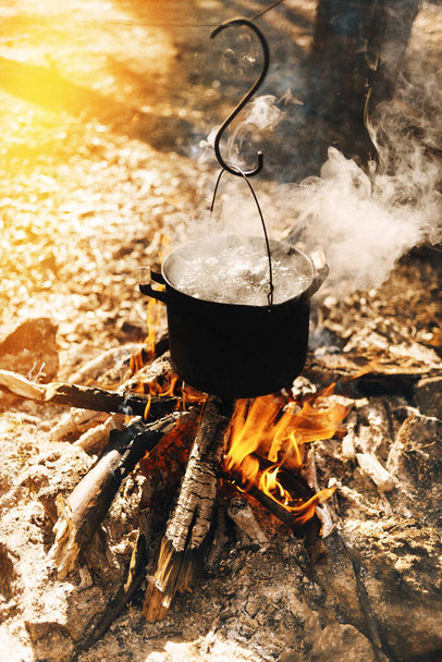 cooking at the stake. lifestyle, tea at the stake. tourist food in the forest. making tea on a campfire on a camping trip. - Foto, imagen