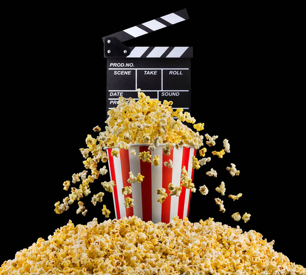 Flying popcorn and film clapper board isolated on black background, concept of watching TV or cinema. - Foto, Bild