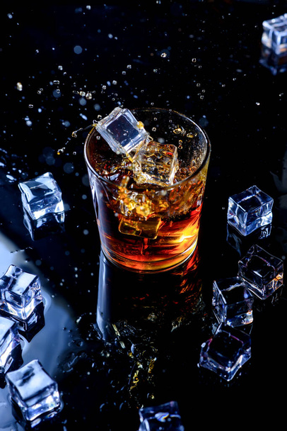 上から黒の背景に氷のキューブとウィスキー。黒の背景にスコッチと氷のキューブのガラス - 写真・画像