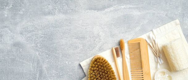 Set of personal hygiene accessories on stone background. Zero waste, plastic free SPA bath products. Flat lay, top view towel with body brush, bamboo toothbrushes, hair comb, ear sticks, loofah sponge - Foto, immagini