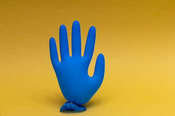 Blue medical glove inflated. On yellow background with copy space. - Foto, afbeelding