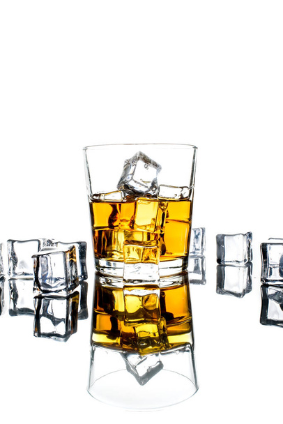Glass of whiskey and ice cubes.Isolated shot of whiskey.Glass of scotch and ice cubes on a white background. - Photo, Image