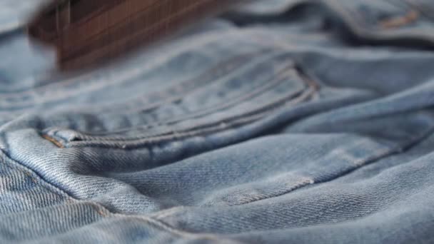 Oryginalny skórzany portfel spada na jeansową kurtkę. Stary brudny brązowy dodatek w niebieskich dżinsach. Koncepcja kryzysu finansowego spowodowanego pandemią koronawirusów - Materiał filmowy, wideo