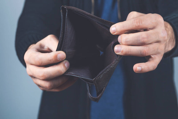 young man hand empty wallet on dark background - Фото, изображение