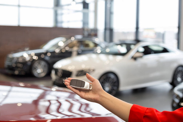 Dealer woman holding keys to a new car. Modern and prestigious vehicles. For use as a background. - Zdjęcie, obraz