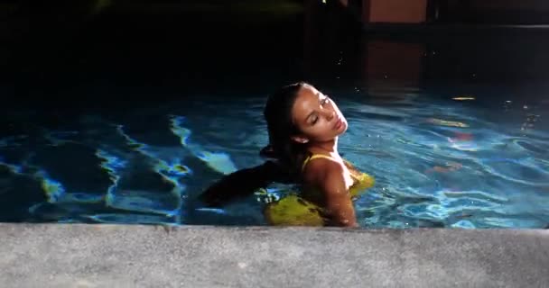 Сексуальная женщина в бассейне ночью в желтом бикини - Кадры, видео