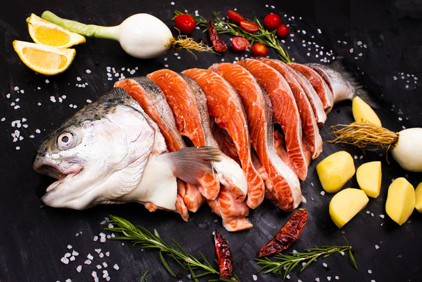 Steaks van rauwe zalm. Verse vis met specerijen, tomaten, uien, citroen, aardappelen en olijfolie. - Foto, afbeelding