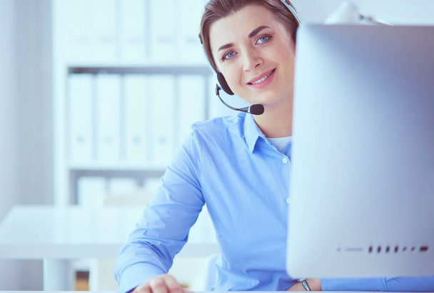 Serious pretty young woman working as support phone operator with headset in office - Foto, Bild
