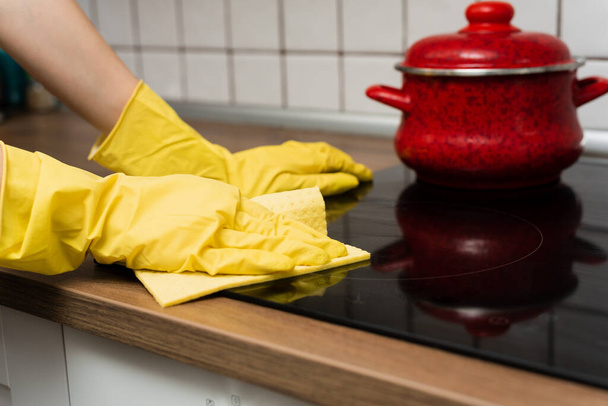 Ktoś myje kuchenny piec w żółtych rękawiczkach. Ktoś sprząta kuchnię szmatą.. - Zdjęcie, obraz
